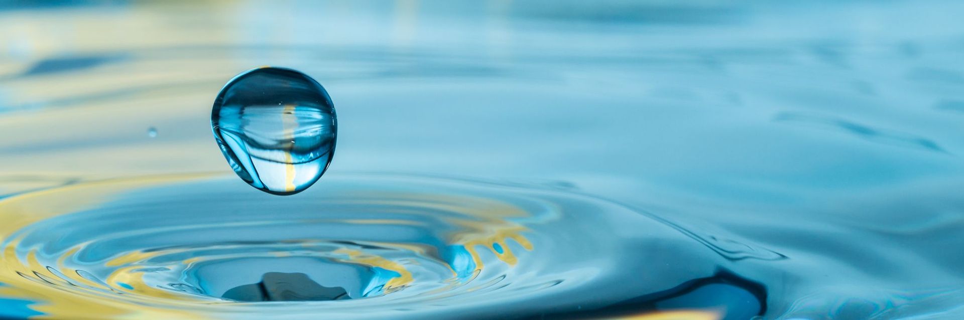 Wassertropfen trifft auf Wasseroberfläche Nahaufnahme